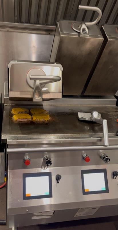 Taylor two-sided grill opening with burger patties with cheese cooked on the grill