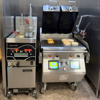 Taylor two-sided grill cooking burgers and warming buns with henny penny open fryer