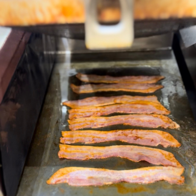 Close up bacon cooking on Taylor two-sided grill