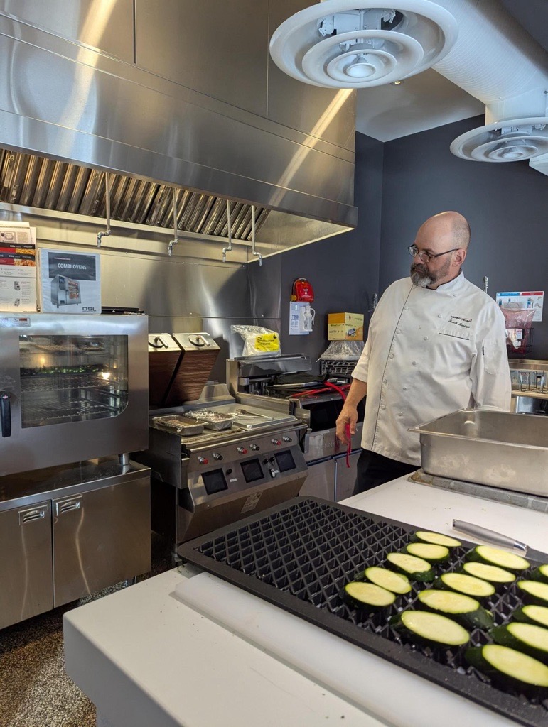 Chef in front of combi oven and two-sided grill automation to help for labour shortages