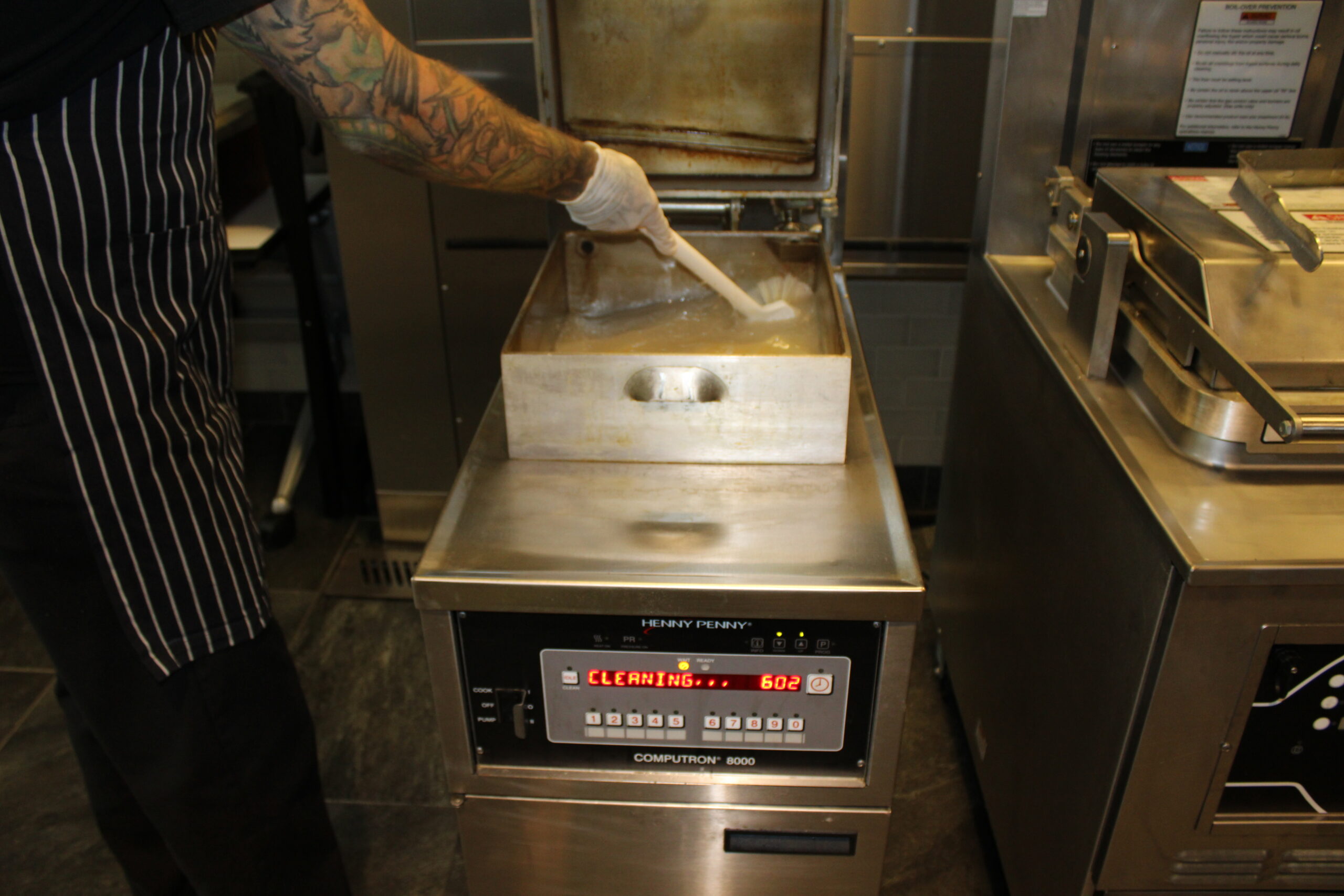 Team member performing routine commercial fryer oil maintenance