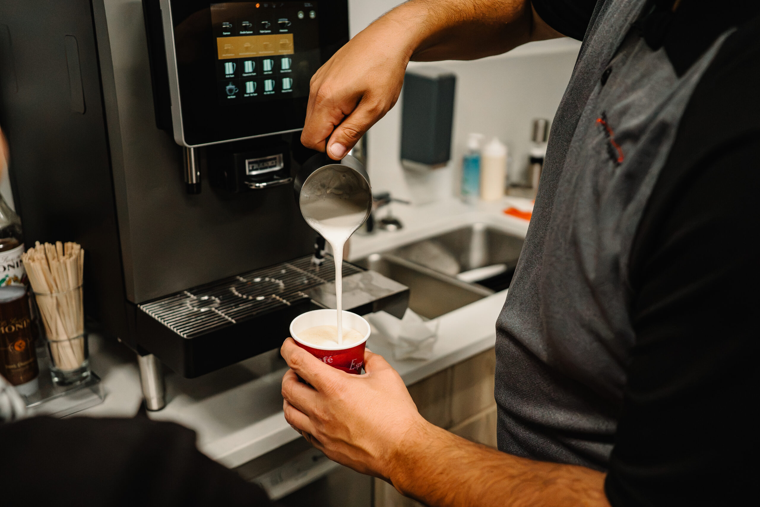 S700 barista pouring steamed milk into espresso drink to make a latte